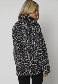 Leopardskinnäslagen fleecejacka i marinblått och beige, med krage, långa ärmar och ett mjukt, strukturerat tyg med avslappnad passform.