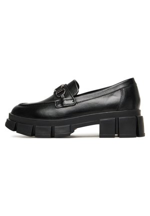 Czarny skórzany mokasyn z grubą, segmentowaną podeszwą platformową i metalową klamrą na przodzie, widok z boku na białym tle.