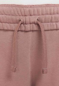 Los joggers de algodón rosa presentan una cinturilla acanalada con cordones ajustables, una textura suave y detalles de costura sutiles a lo largo de las costuras.