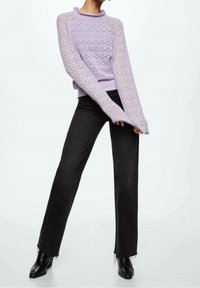 Pull en lilas tricoté avec un col à volants, associé à un jean noir à jambes droites. La texture comprend un point de motif et des ourlets effilochés.