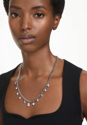 Collier en chaîne argentée avec différentes pierres précieuses, présentant des formes en goutte et rectangulaires, porté sur un haut sombre.