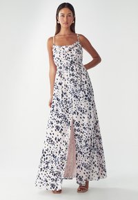 Robe maxi en tissu léger avec un fond rose et des pois navy et bleus, décolleté froncé et fente sur le côté.
