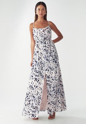 Robe maxi en tissu léger avec un fond rose et des pois navy et bleus, décolleté froncé et fente sur le côté.