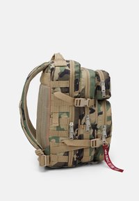 Plecak w camouflaged wzorze, wykonany z trwałego materiału, z wieloma zamykanymi na zamek przegrodami, siateczkowymi akcentami oraz uchwytem do noszenia.