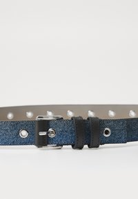 Cinturón de mezclilla azul con acentos de cuero negro. Presenta hebilla metálica, agujeros de ajuste y bucles de sujeción dobles. Textura suave.