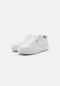 Sneaker bianchi con tomaia in pelle liscia, punta rotonda, design con lacci e suola in gomma texturizzata caratterizzata da accenti discreti vicino ai lacci.