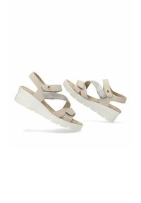 Sandalias beige con dos correas cruzadas, una en tejido suave y otra con acabado metálico. Suela gruesa blanca para mayor confort. Detalle de hebilla ajustable.