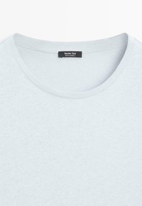 T-shirt en coton bleu clair à col rond avec couture visible et étiquette noire Massimo Dutti cousue à l'intérieur du col.