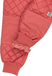 Quiltede vanter i blødt koralfarvet stof med et tekstureret diamantmønster, elastiske manchetter og flæsekant for en tætsiddende pasform og varme.