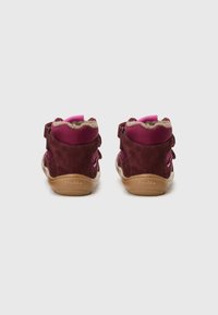 Baskets montantes en daim marron avec des accents roses, des sangles en velcro et une semelle en caoutchouc beige. Doublées d'un matériau doux pour le confort.