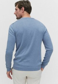 Blått stickat tröja med långa ärmar och rund halsringning, med ribbade ärmslut och nederkant, visad från baksidan.