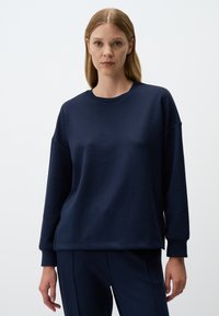 Felpa blu navy realizzata in morbido tessuto. Presenta una vestibilità comoda, scollo rotondo e maniche lunghe. Dettagli delle cuciture sulle spalle e sui polsini.