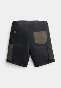 Shorts noirs avec une taille élastique, comprenant deux poches arrière : une noire et une olive verte avec des surpiqûres rouges. Comprend une poche cargo.
