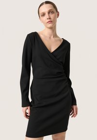 Schwarzes Wickelkleid mit langen Ärmeln, V-Ausschnitt und gerafften Details an der Taille. Hergestellt aus glattem, dehnbarem Stoff.