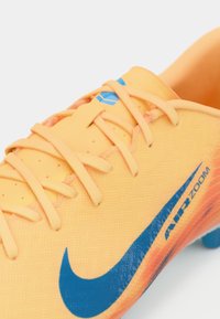 Nike Air Zoom futbola čības ar spilgti oranžu augšdaļu un ziliem akcentiem, teksturētu materiālu un izvēles dizainu ar šņorēm.
