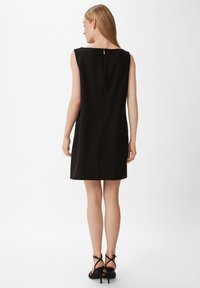 Schwarzes ärmelloses Kleid mit geradem Schnitt, ausgestattet mit einem Reißverschluss auf der Rückseite und minimalistischem Design. Glatte Textur, knielang und klassischer Schnitt.