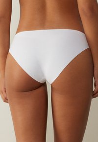 Hipsters en coton blanc avec une texture lisse et un design minimaliste, présentant une taille basse et sans coutures visibles.
