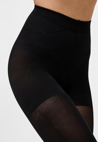 Leggings nere a vita alta con una cintura testurizzata e tessuto trasparente. Presentano una finitura liscia e una vestibilità aderente, evidenziando la forma delle gambe.