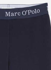 Marineblauwe legging met een brede elastische tailleband waarop de tekst "Marc O’Polo" in het wit is gedrukt. Gemaakt van zachte, elastische stof.