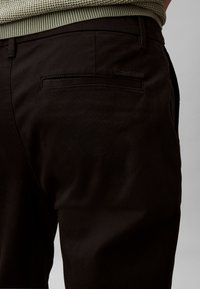 Mustad, kitsad püksid, mille tagataskul on peen Calvin Kleini logo. Valmistatud siledast kangast klassikalise lõikega.