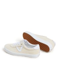 Beige suede sneakers with white laces and accents, featuring a textured gum rubber sole and minimalistic design.