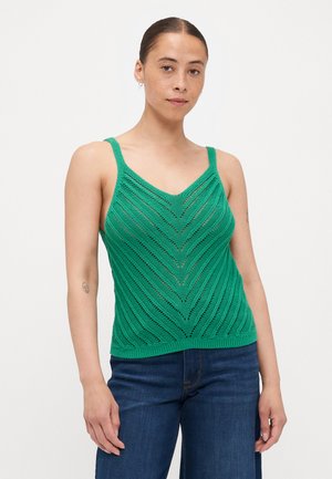 Top din tricot verde, cu decolteu în V și bretele subțiri, având un model în zigzag și tiv ribbed, asortat cu pantaloni din denim.