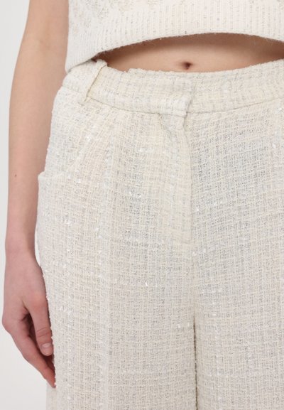 Helle, strukturierte Stoffhosen mit einem gewebten Muster, ausgestattet mit Seitentaschen und einem glatten Bündchen. Weiches und leichtes Material.