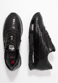 Černé tenisky s texturovaným hadím vzorem. Mezi vlastnosti patří lesklý povrch, černé tkaničky a boční zip pro snadný přístup.