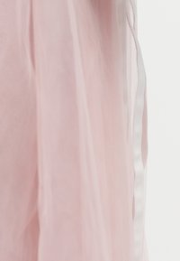 Světlounce růžová průsvitná látka se mírně pokrčenou texturou, s bílou saténovou stuhou podél okraje. Jemný a plynulý design.