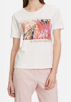 Valkoinen puuvillapaita, jossa on värikäs graafinen suunnittelu, jossa on tekstiä, abstrakteja muotoja ja kuvioita vaaleanpunaisessa, ruskeassa ja mustassa sävyssä. Lyhyet hihat.