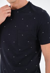 Námořnické tričko s krátkým rukávem vyrobené z bavlny, s malými bílými vzory deštníků a kapsou na hrudi, s kulatým výstřihem.