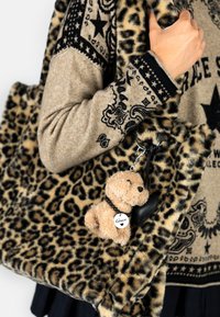 Leopard-print faux fur bag with a plush teddy bear keychain. The sweater has a beige base with black bandana patterns and a star design.