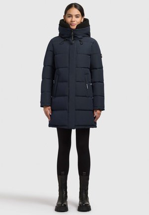 Cappotto imbottito blu navy con colletto alto, design imbottito e due tasche laterali. Il cappotto presenta una chiusura frontale con zip ed è realizzato in tessuto liscio.