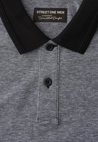 Polo gris texturé pour homme avec col noir, deux boutons noirs et étiquette indiquant « STREET ONE MEN Experience Unmatched Comfort. »