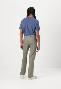 Blue short-sleeve t-shirt paired with olive green pants. The outfit features a relaxed fit and simple design, complemented by beige sneakers.