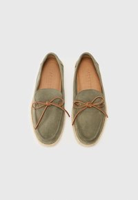 Mocassini in suede verde oliva, con dettaglio in pelle a fiocco annodato, suola in juta e punta leggermente arrotondata. Marchio impresso sulla soletta.