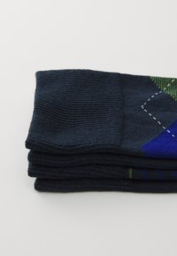 Dark blue socks stacked, featuring a ribbed texture with green and blue geometric patterns and contrasting stitched accents.
