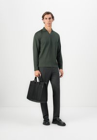 Mørkegrøn langærmet polo, sorte stribede bukser og en sort læder tote bag med flere rum, parret med sorte sko.