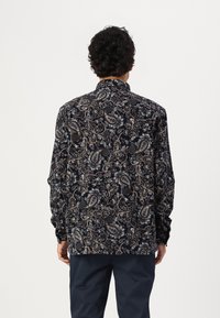 Cămașă navy cu model paisley, având modele complicate în nuanțe de bej și alb, mâneci lungi, guler și o croială lejeră. Materialul pare neted.