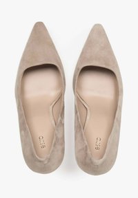 Beige suède hoge hakken schoenen met een puntige neus en uitsparingen aan de zijkanten, met een gladde binnenvoering en gouden branding op de binnenzool.