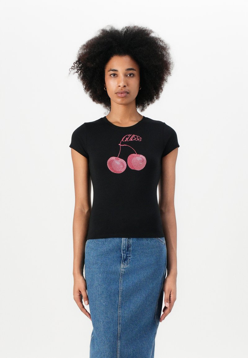 Maglietta nera a maniche corte con grafica di ciliegia rosa glitterata, abbinata a una gonna di jeans. Design semplice e aderente.