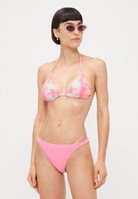 Cvjetni bikini set s uzorkom u ružičastoj i mint boji. Gornji dio ima trokutasti dizajn, dok donji dio ima rebrastu teksturu.