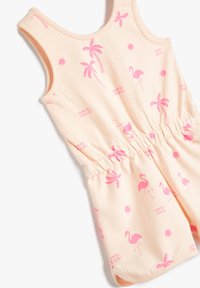 Ljus persiko ärmlös jumpsuit med dragsko i midjan, mönster av rosa flamingo, palmer och sol, tillverkad av bekväm bomullsmaterial.