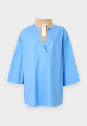 Camisa oversize azul claro con mangas tres cuartos y un cuello beige en contraste, con un escote en V profundo y una etiqueta de ropa.