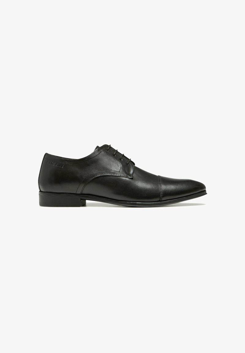 Chaussure habillée en cuir noir avec un bout pointu, surface lisse, design à lacets et détails de couture subtils. Talon bas et plat.