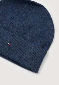 Beanie blu scuro in maglia con risvolto e un piccolo logo rettangolare rosso, bianco e blu sul bordo del risvolto.