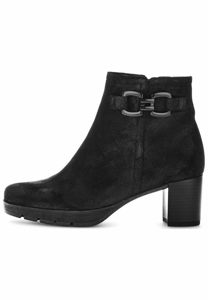 Bottine en suède noir avec un bout arrondi, un talon carré et deux boucles métalliques en accent sur le côté. Fini texturé sur l'ensemble.