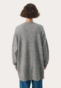 Pulover gri supradimensionat cu un tricot texturat, guler rotund, umeri căzuți și tiv côtelat. Purtați-l cu blugi albaștri.