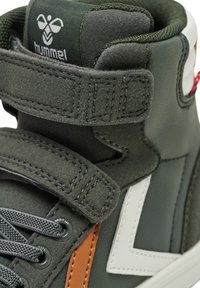 Höga sneakers i mörkgrön läder och mocka, med vitt logotyp, bruna detaljer, runda snören och kardborreband. Strukturerad yta.