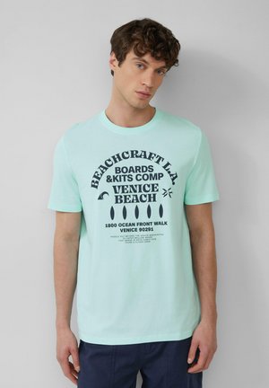Mintgroene katoenen t-shirt met grafische print en tekst. Korte mouwen, ronde hals, relaxed fit en een gladde textuur.
